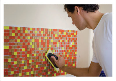 Backsplash DIY: Using the grout float to apply pressure on the mosaic tiles